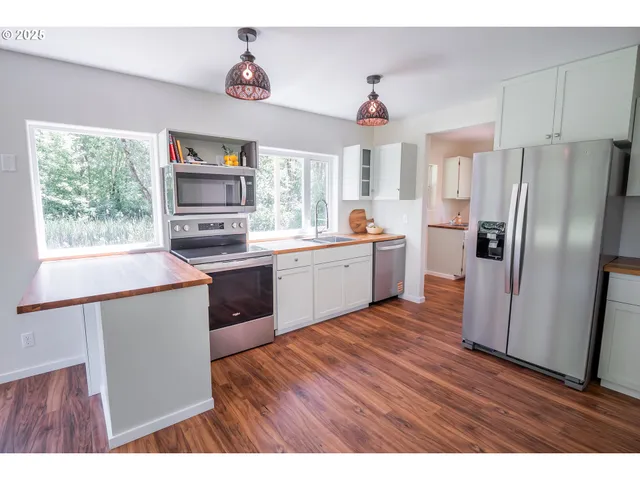 a kitchen with stainless steel appliances a sink cabinets and wooden floor