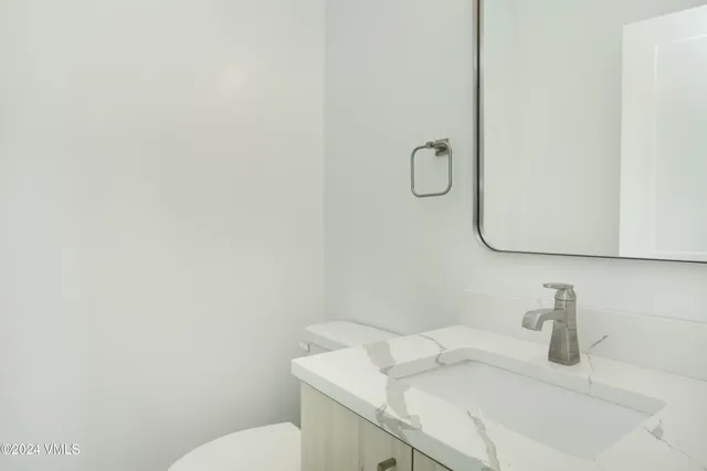 a bathroom with a granite countertop sink a toilet and mirror