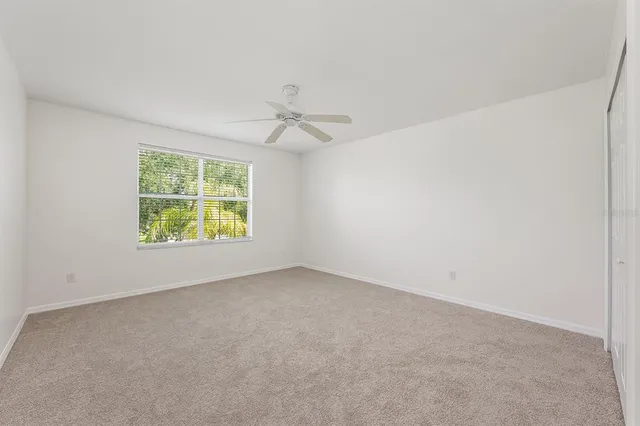 an empty room with chandelier fan and windows