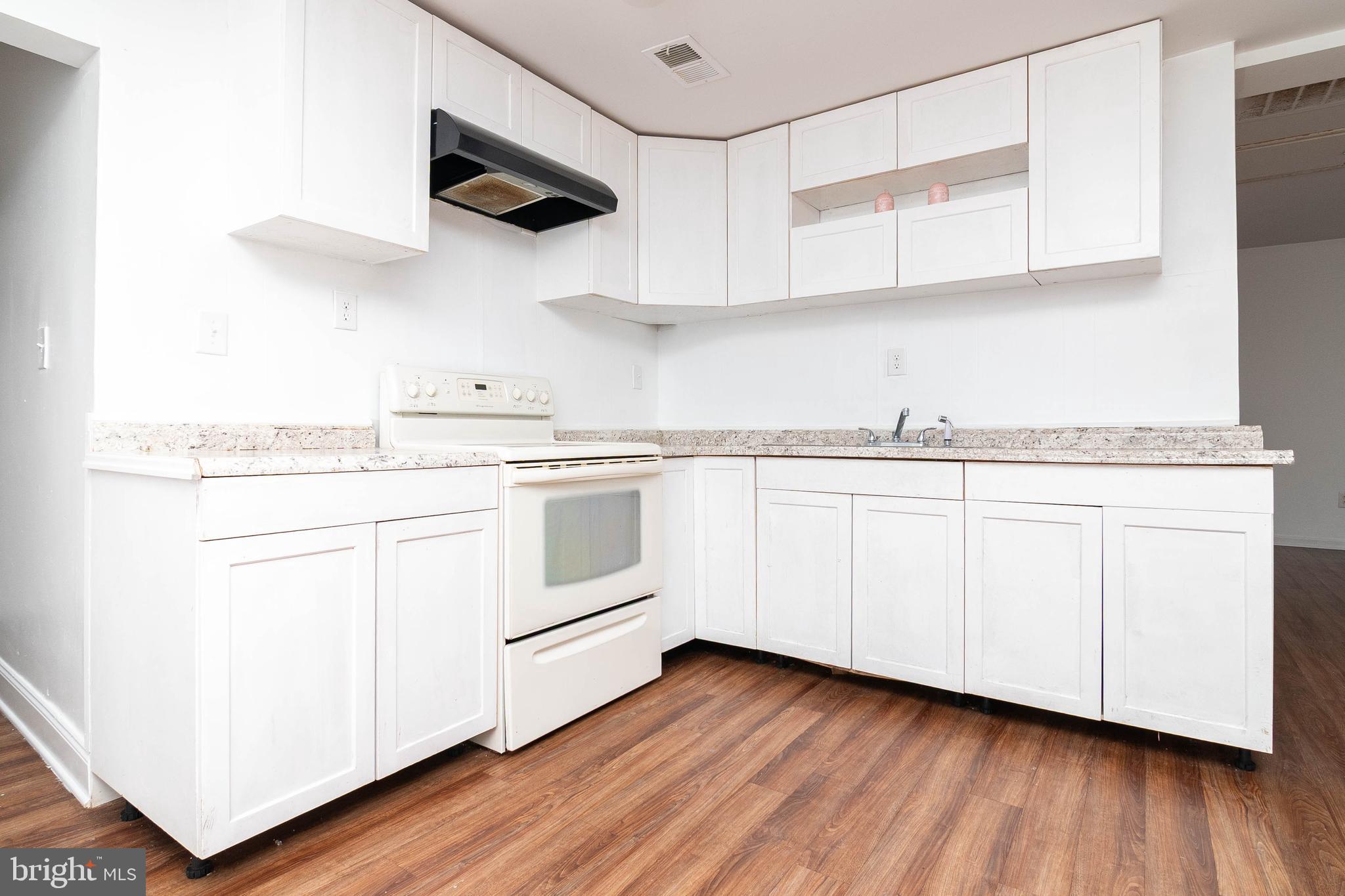 235 West 10th Street Laurel, DE 19956 - Photo 9 of 44 a kitchen with white cabinets stainless steel appliances and wooden floor