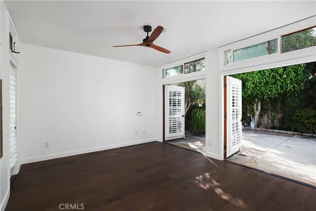 a view of a big room with wooden floor ceiling fan and windows