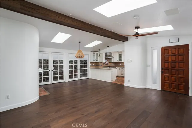 a view of an empty room with wooden floor kitchen view and a window