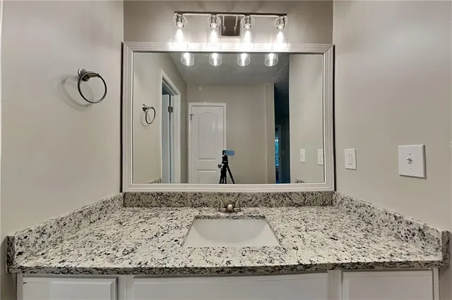 a bathroom with a granite countertop sink and a mirror