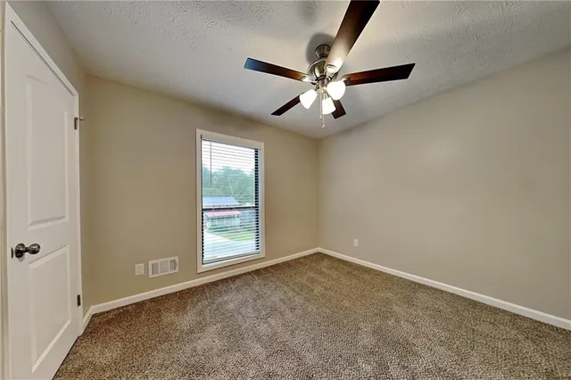 an empty room with windows and fan