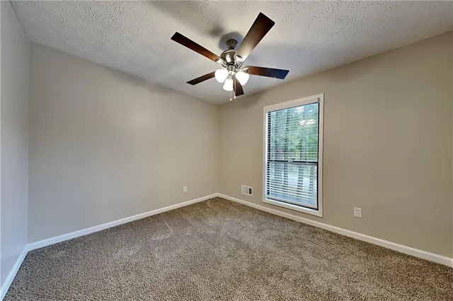 an empty room with ceiling fan and windows