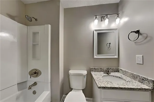a bathroom with a granite countertop sink toilet and shower