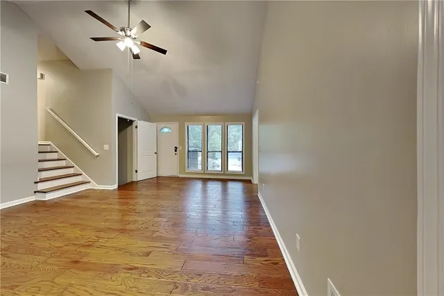 a view of an empty room with wooden floor and a window