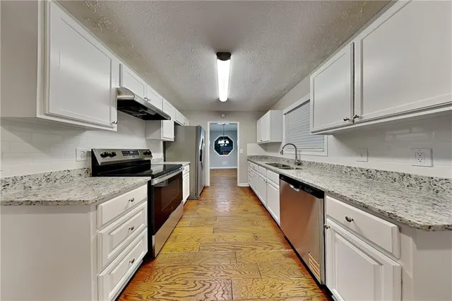 a large kitchen with stainless steel appliances granite countertop a stove sink and cabinets