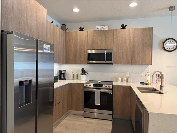 a kitchen with stainless steel appliances granite countertop a refrigerator a stove a sink and a microwave
