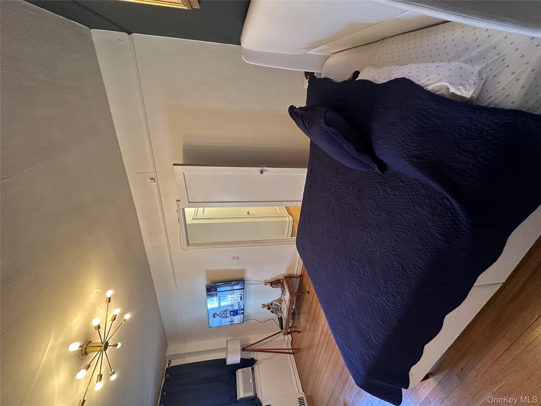 86-10 34th Avenue, Unit 624 Queens, NY 11372 - Photo 13 of 20 Bedroom featuring wood finished floors and a chandelier