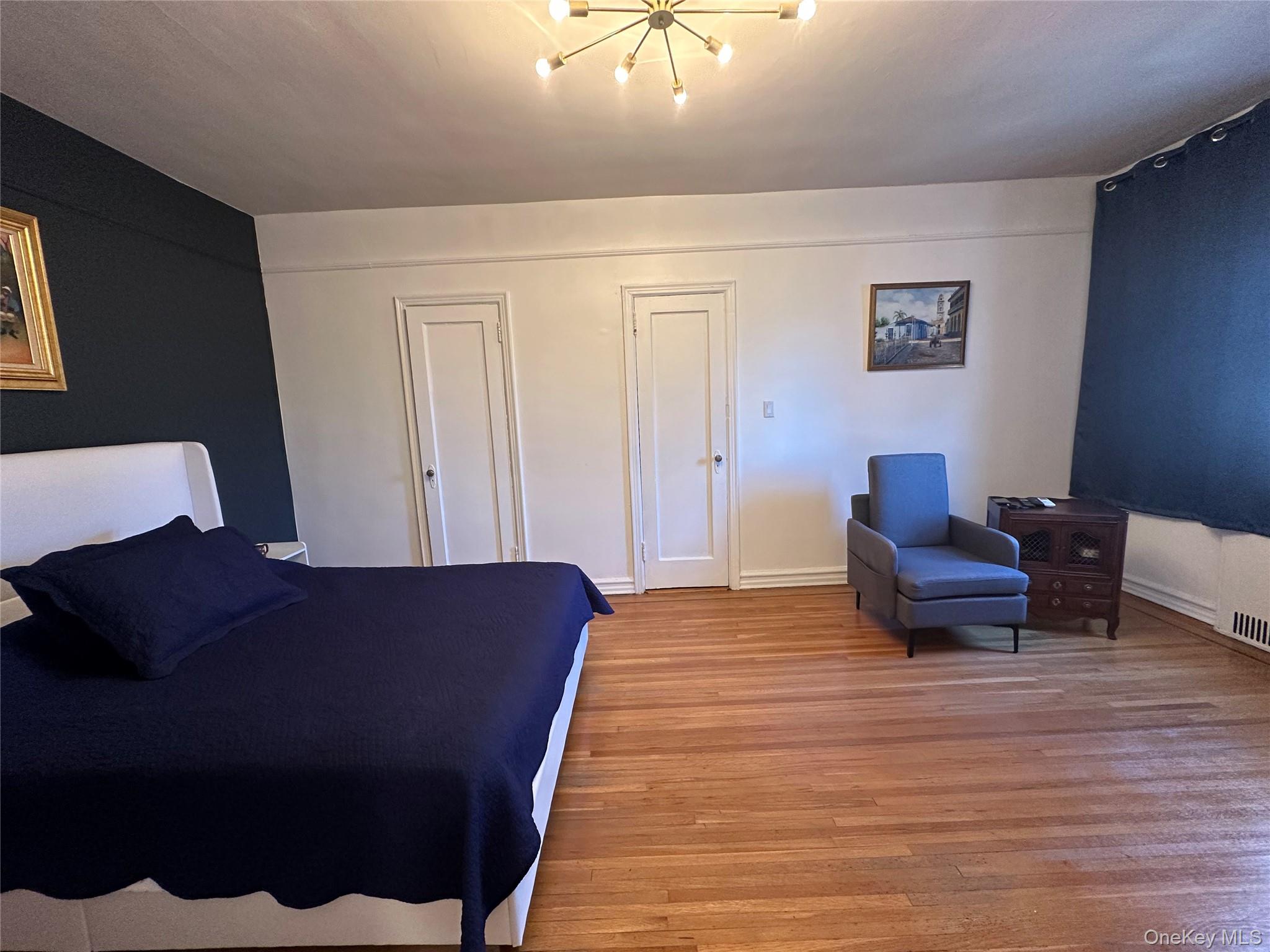 86-10 34th Avenue, Unit 624 Queens, NY 11372 - Photo 14 of 20 Bedroom featuring multiple closets, light wood-style floors, and a chandelier