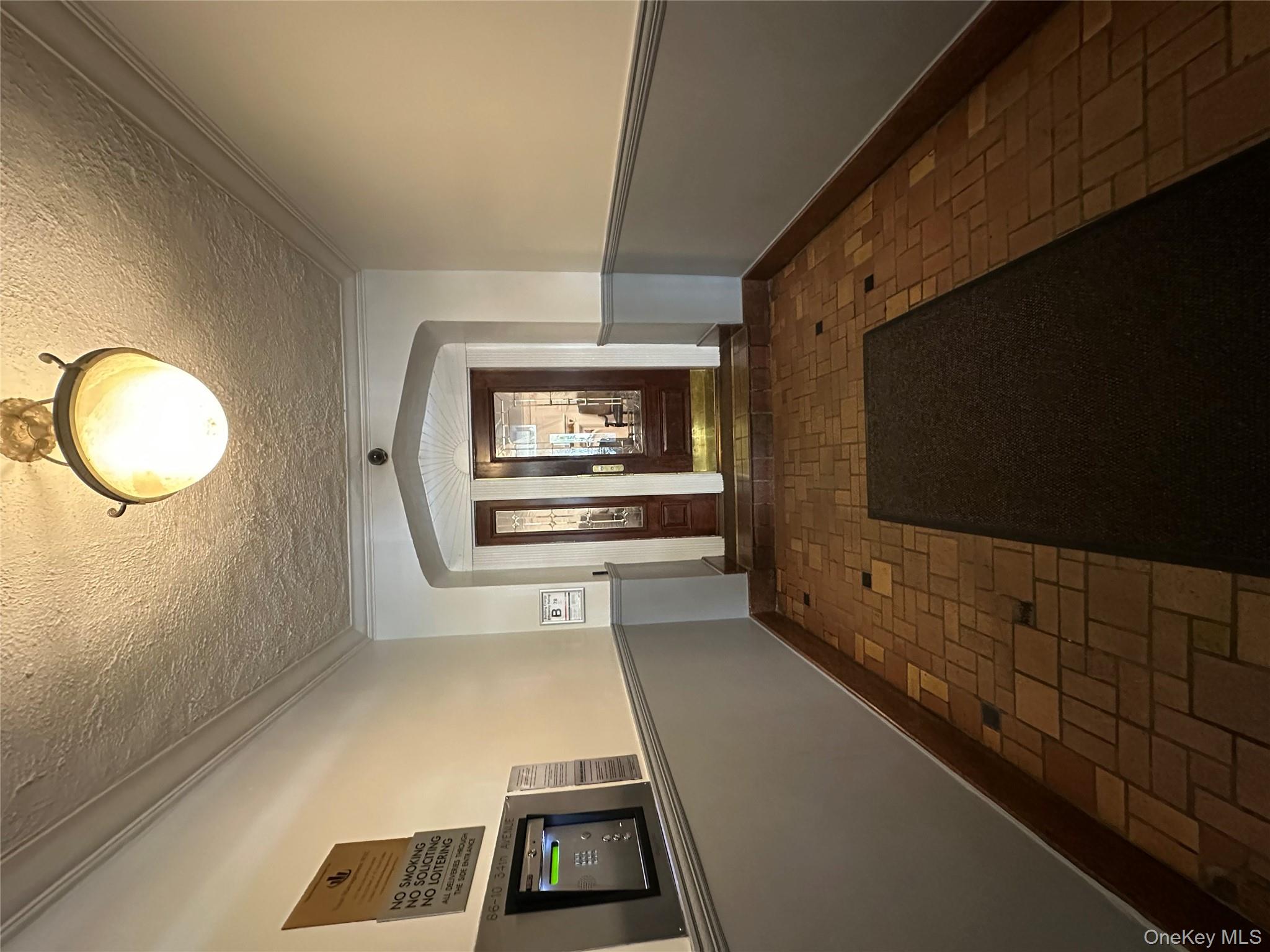 86-10 34th Avenue, Unit 624 Queens, NY 11372 - Photo 20 of 20 Corridor featuring crown molding, a textured ceiling, arched walkways, and brick floors