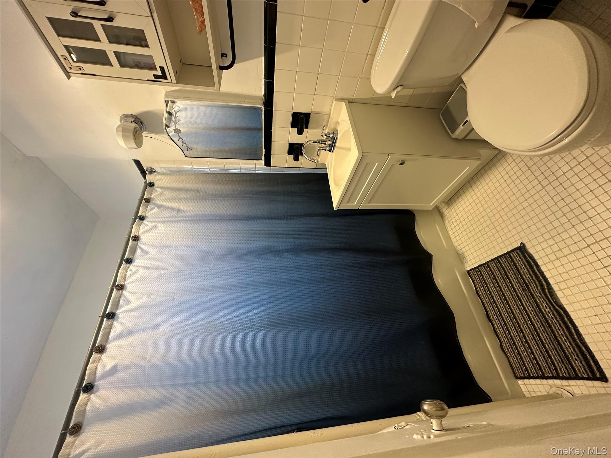 86-10 34th Avenue, Unit 624 Queens, NY 11372 - Photo 10 of 20 Full bathroom with tile walls, vanity, shower / bath combo with shower curtain, and light tile patterned floors