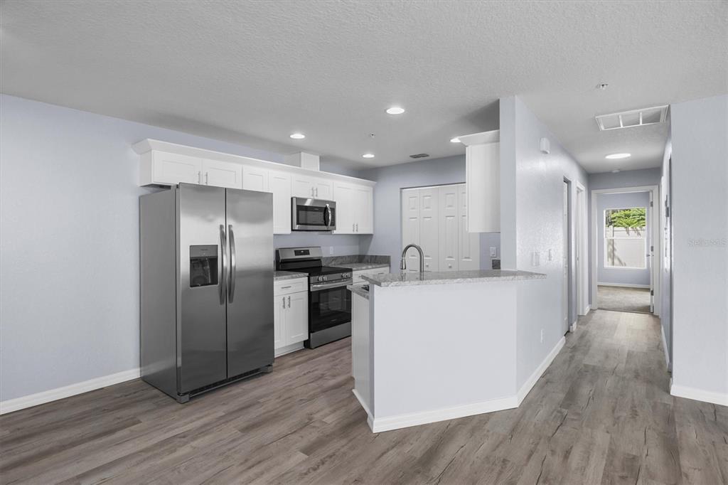 4153 Oak Loop Mulberry, FL 33860 - Photo 4 of 11 a large white kitchen with a refrigerator a stove top oven and wooden floor