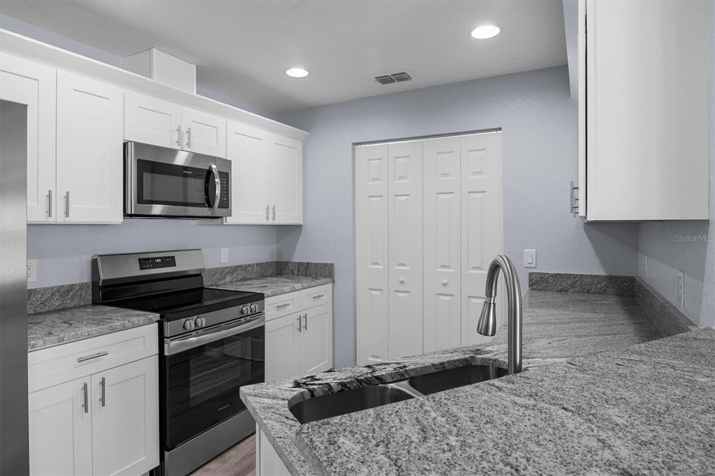 4153 Oak Loop Mulberry, FL 33860 - Photo 5 of 11 a kitchen with granite countertop a stove sink and cabinets