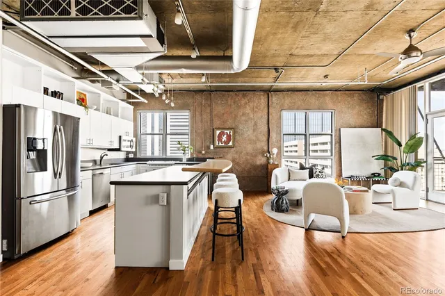 a kitchen with stainless steel appliances granite countertop a refrigerator a sink dishwasher a stove and white countertops with wooden floor