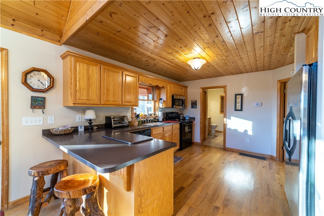 893 Deerwood Road Piney Creek, NC 28663 - Photo 17 of 50 a kitchen with granite countertop a refrigerator a stove a sink a dining table and chairs with wooden floor