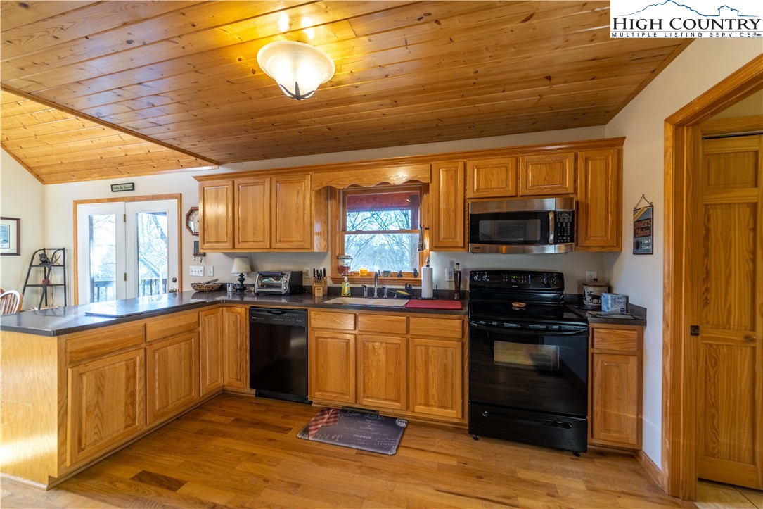 893 Deerwood Road Piney Creek, NC 28663 - Photo 18 of 50 a kitchen with stainless steel appliances granite countertop a stove top oven a sink dishwasher a dining table and chairs with wooden floor
