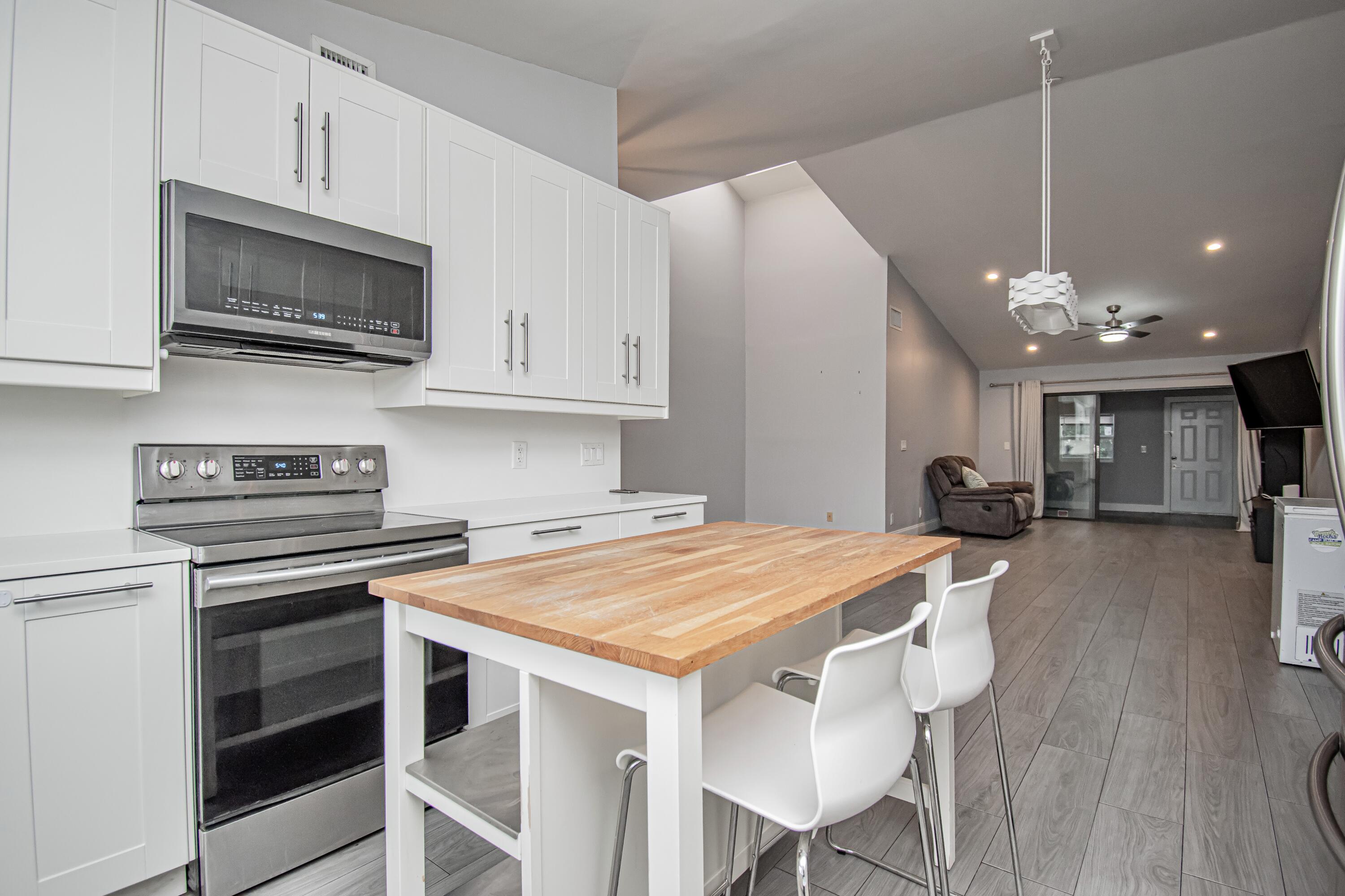 7706 Solimar Circle Boca Raton, FL 33433 - Photo 7 of 28 a kitchen with stainless steel appliances a stove a microwave a sink a stove and white cabinets