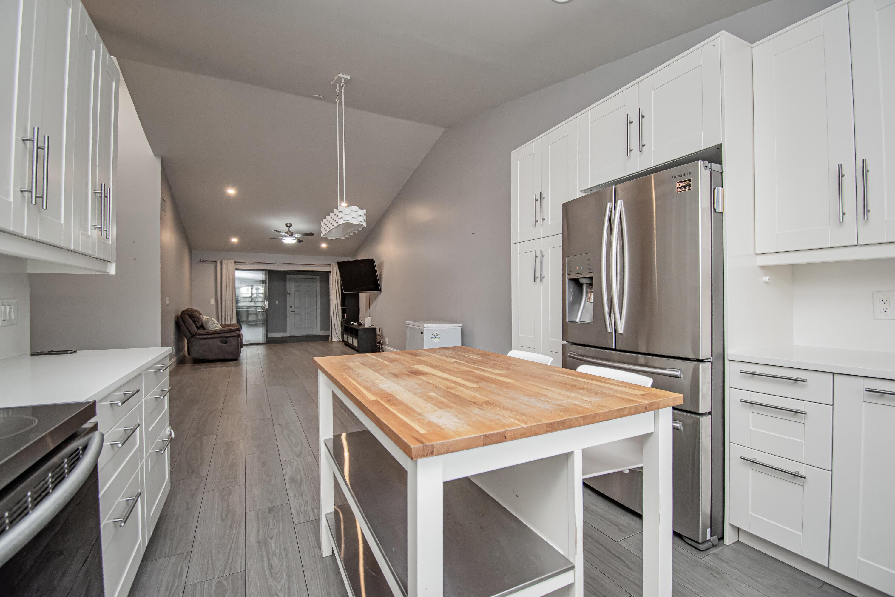 7706 Solimar Circle Boca Raton, FL 33433 - Photo 8 of 28 a kitchen with kitchen island white cabinets and stainless steel appliances