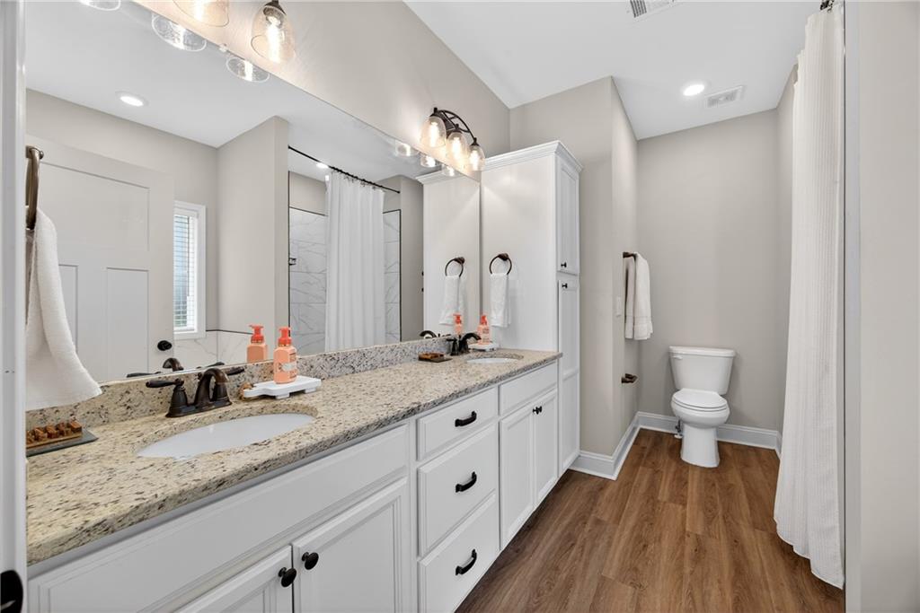 30 Buffelhead Court Monticello, GA 31064 - Photo 18 of 37 a bathroom with a granite countertop double vanity sink a mirror and a toilet