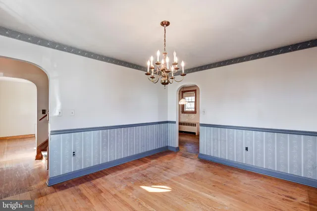 a view of a hallway with wooden floor and chandelier