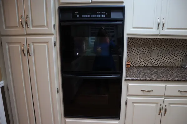 a kitchen with granite countertop a stove a sink dishwasher and white cabinets