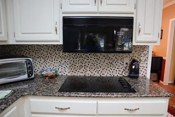 a kitchen with granite countertop a sink stove and cabinets