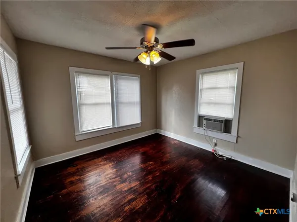 a view of an empty room with window and chandelier fan