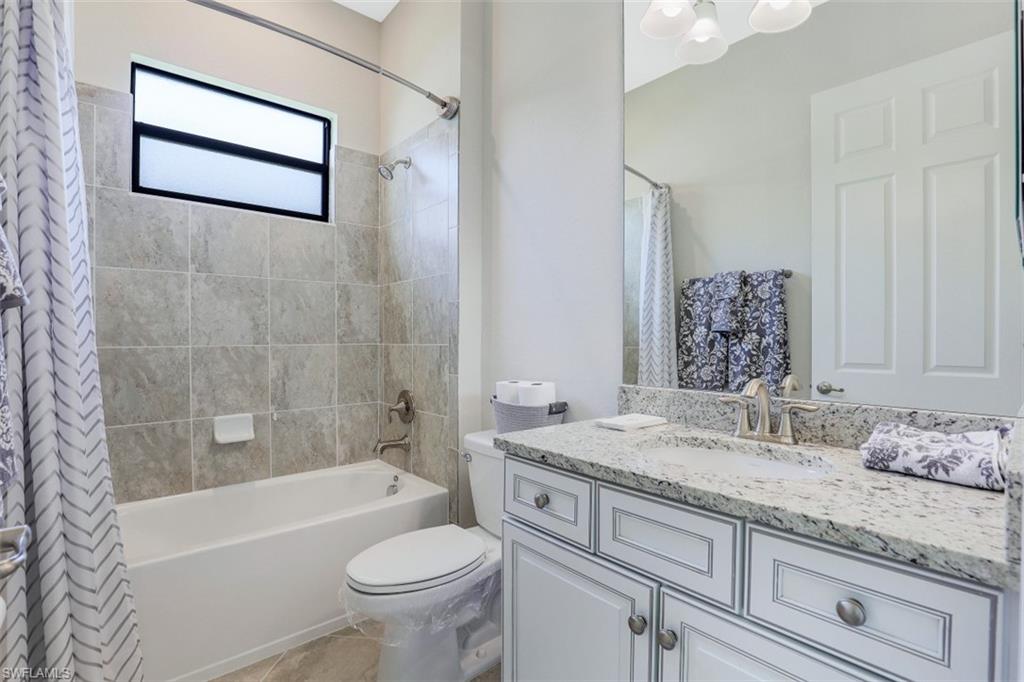 2134 Antigua Lane Naples, FL 34120 - Photo 19 of 31 a bathroom with a granite countertop sink a toilet a mirror a bathtub and shower