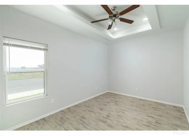 an empty room with a window and a ceiling fan