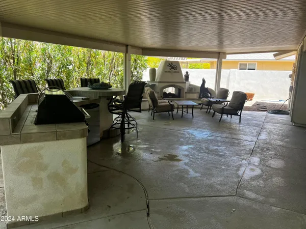a view of a patio with table and chairs under an umbrella next to a yard