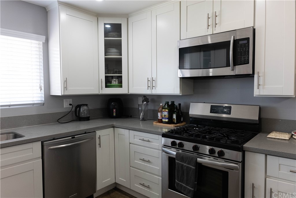 a kitchen with stainless steel appliances granite countertop grey cabinets a stove a sink and dishwasher