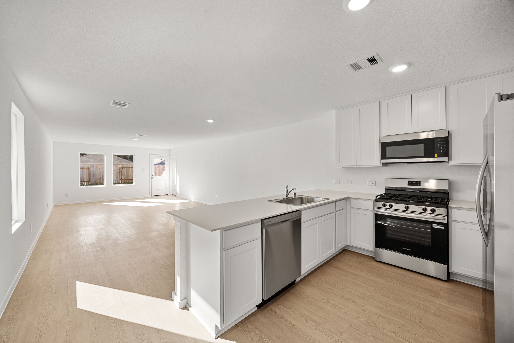 31433 Moore Road Magnolia, TX 77354 - Photo 7 of 25 a kitchen with stainless steel appliances granite countertop a stove top oven a sink a refrigerator and white cabinets with wooden floor