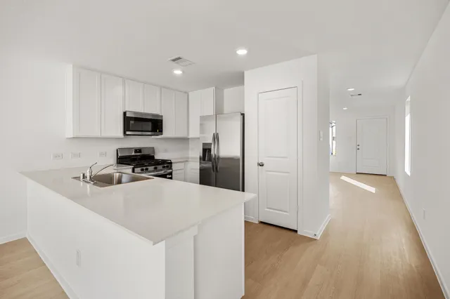 a kitchen with granite countertop a refrigerator a sink a stove a microwave and wooden floor