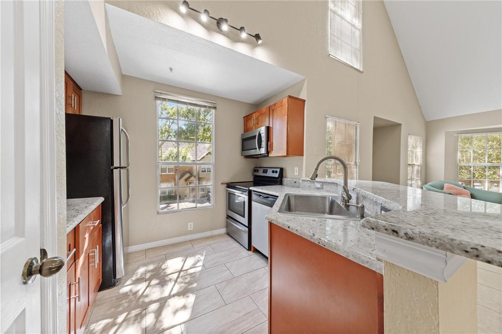 6340 Raleigh Street, Unit 1011 Orlando, FL 32835 - Photo 18 of 68 a large kitchen with granite countertop a sink stainless steel appliances and cabinets
