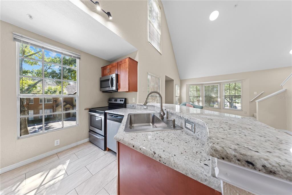 6340 Raleigh Street, Unit 1011 Orlando, FL 32835 - Photo 19 of 68 a large kitchen with granite countertop a sink and a counter top space