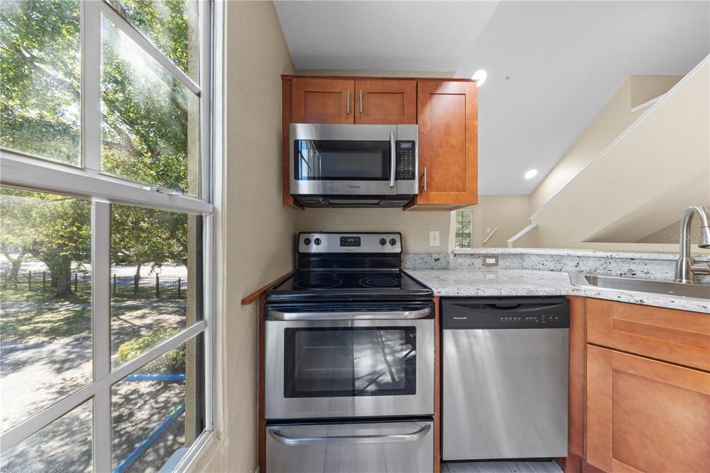 6340 Raleigh Street, Unit 1011 Orlando, FL 32835 - Photo 20 of 68 a kitchen with granite countertop a stove sink and microwave