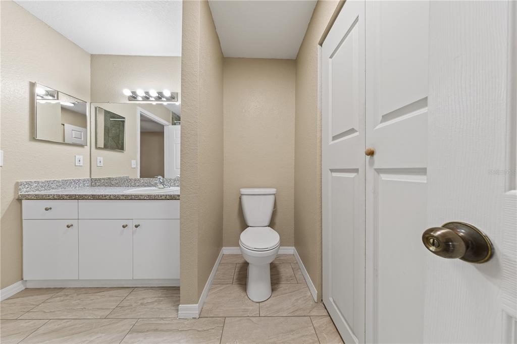 6340 Raleigh Street, Unit 1011 Orlando, FL 32835 - Photo 30 of 68 a bathroom with a granite countertop toilet and a sink