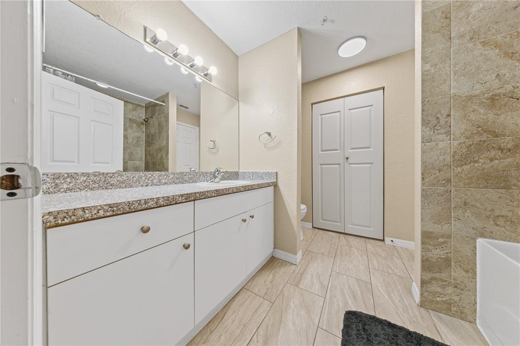 6340 Raleigh Street, Unit 1011 Orlando, FL 32835 - Photo 36 of 68 a spacious bathroom with a granite countertop sink a mirror and a shower