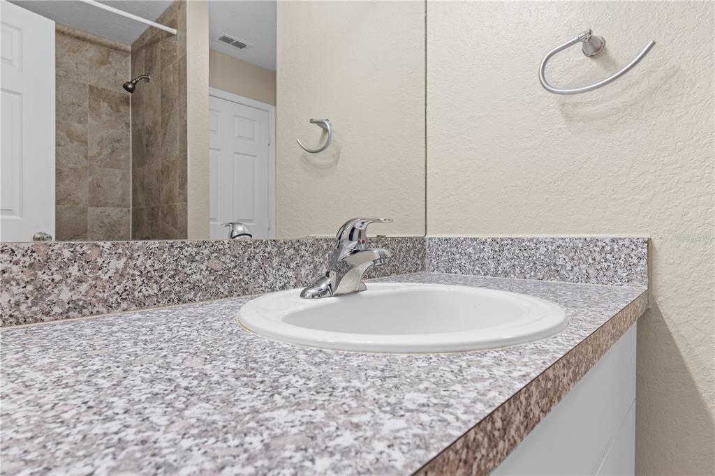 6340 Raleigh Street, Unit 1011 Orlando, FL 32835 - Photo 37 of 68 a bathroom with a granite countertop sink a mirror and a bathtub