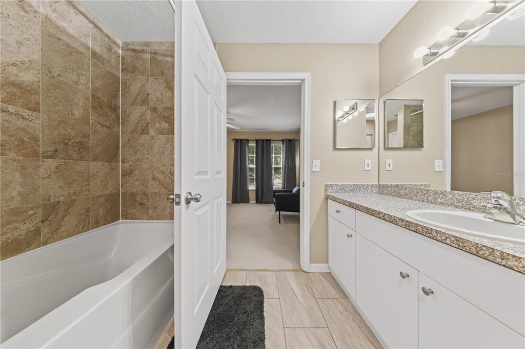 6340 Raleigh Street, Unit 1011 Orlando, FL 32835 - Photo 38 of 68 a bathroom with a granite countertop sink a bathtub and a shower