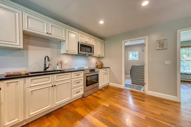 a kitchen with granite countertop a sink cabinets and stainless steel appliances