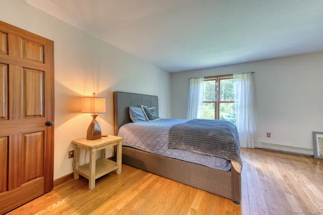 a spacious bedroom with a bed and wooden floor