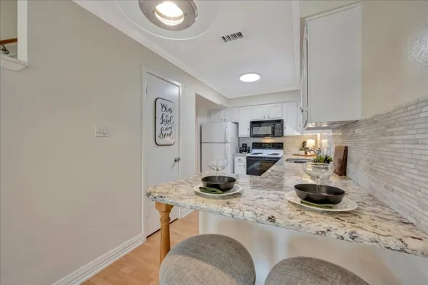 a kitchen with stainless steel appliances granite countertop a sink refrigerator stove and microwave