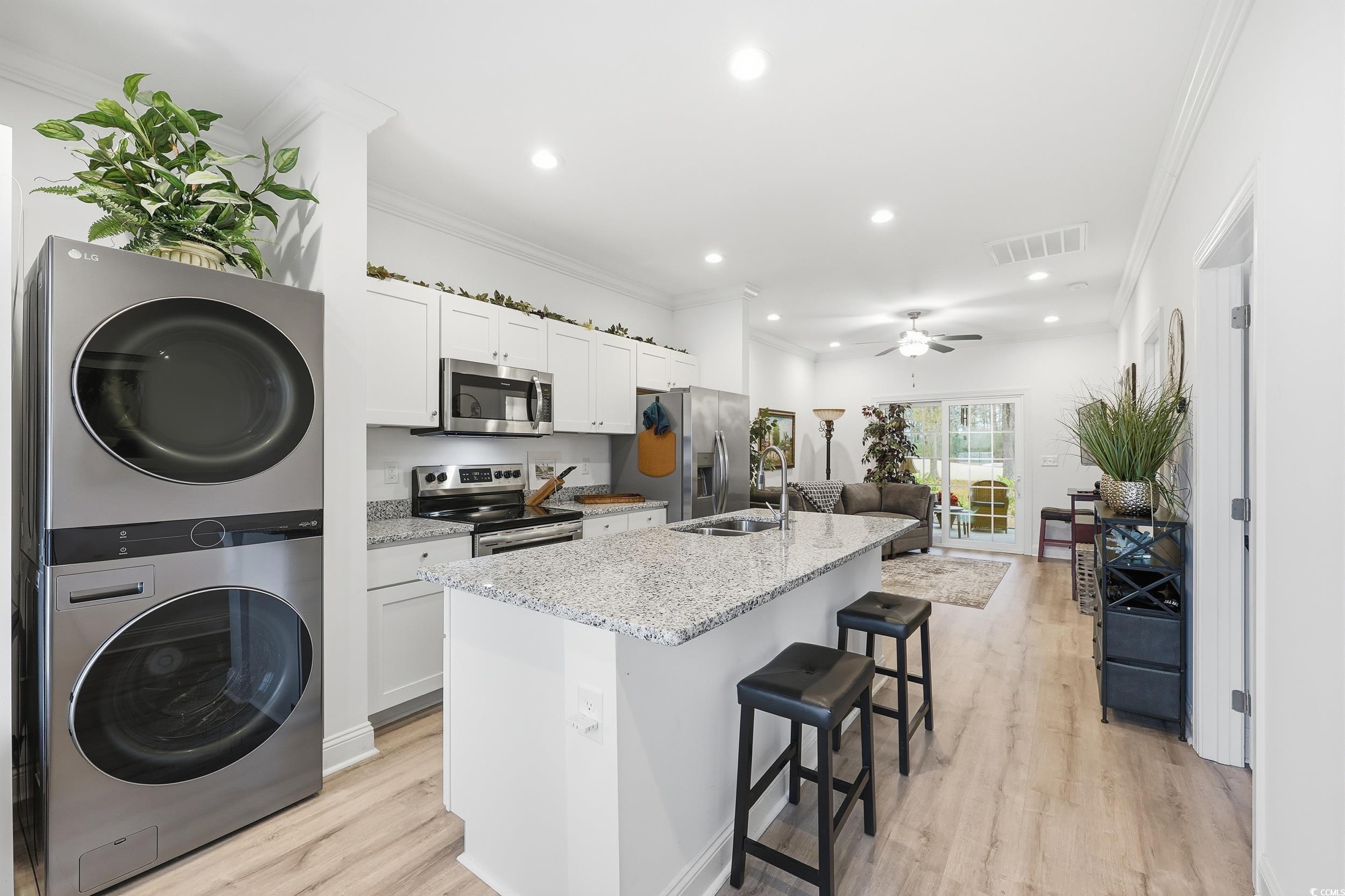 116 Kingsbury Loop, Unit C Conway, SC 29526 - Photo 4 of 32 Kitchen featuring white cabinetry, appliances with stainless steel finishes, a breakfast bar area, ornamental molding, and light stone countertops