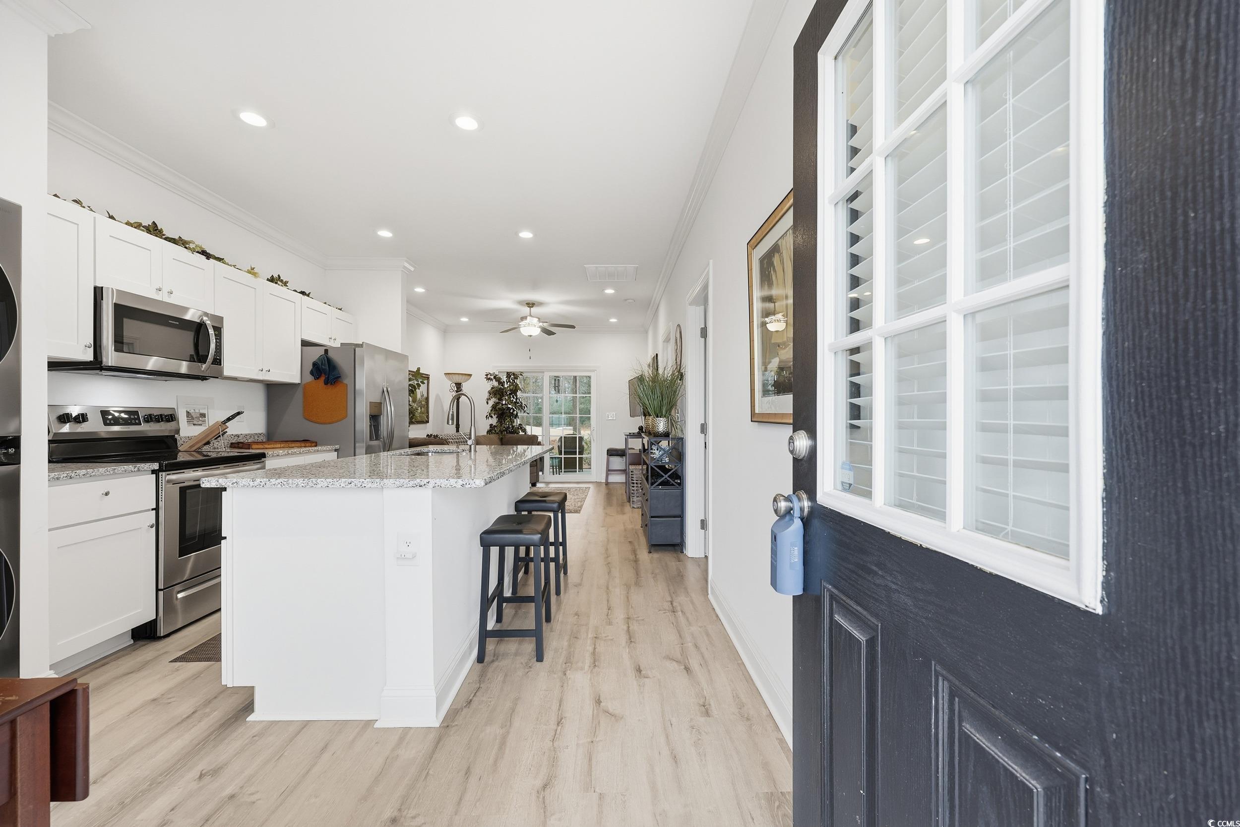 116 Kingsbury Loop, Unit C Conway, SC 29526 - Photo 6 of 32 Kitchen featuring appliances with stainless steel finishes, a breakfast bar area, a kitchen island with sink, ornamental molding, and light stone counters