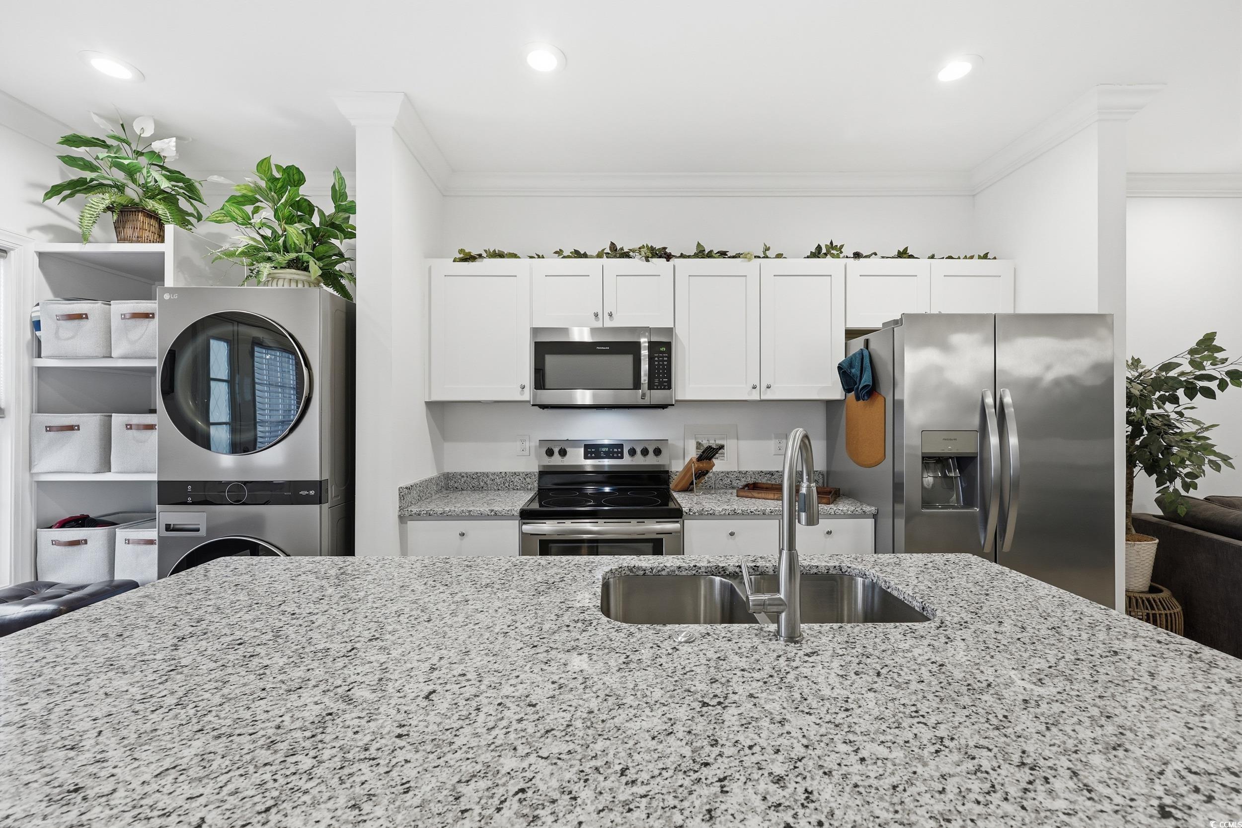 116 Kingsbury Loop, Unit C Conway, SC 29526 - Photo 8 of 32 Kitchen with stainless steel appliances, estacked washer and dryer, light stone countertops, white cabinetry, and ornamental molding