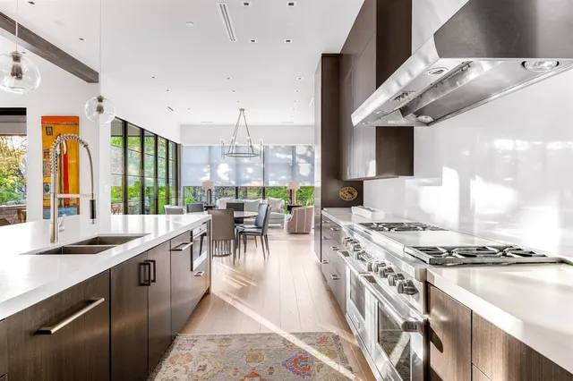 a kitchen with stainless steel appliances granite countertop a stove and a view of living room