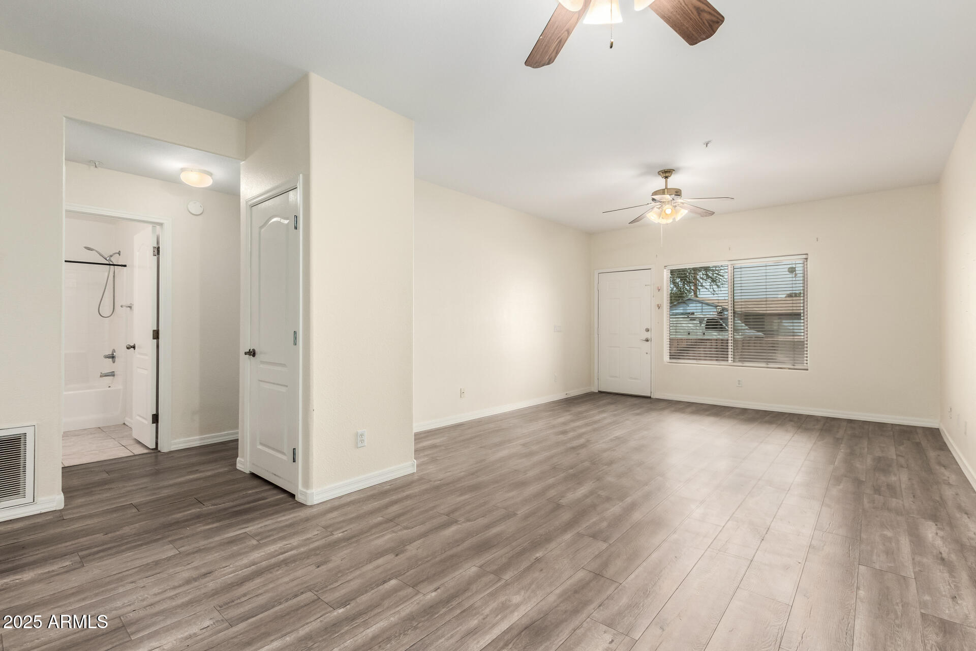 2201 North Comanche Drive, Unit 1104 Chandler, AZ 85224 - Photo 4 of 25 an empty room with wooden floor chandelier fan and windows